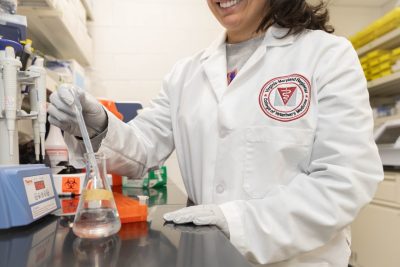 A veterinary student (at center) doing laboratory work with a pipette in the Virginia-Maryland College of Veterinary Medicine multidisciplinary lab.