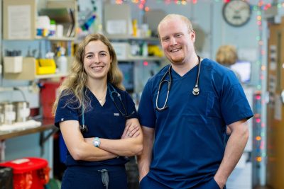 (From left) Samantha Lannon and John Kett posing in blue scrubs with stethoscopes in the anesthesia wing of the Veterinary Teaching Hospital