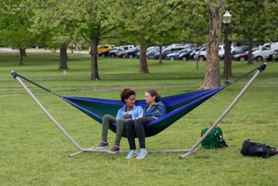 Two students talk while relaxing in a hammock outside to release stress before finals. 