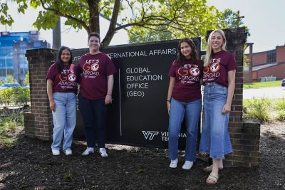 Four students wearing "Go Abroad" T-shirts standing in front of a sign that reads "Global Education Office" 