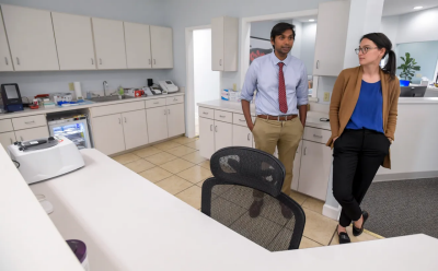 A man and woman stand beside each other in administrative part of doctor's office.